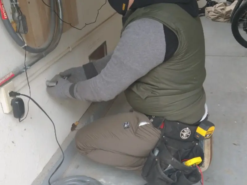 Electrician performing outlet wiring in a Chatham garage